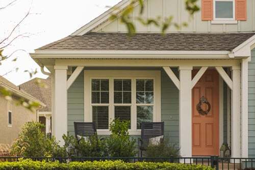Photo of house with neutral color siding and a light red door.