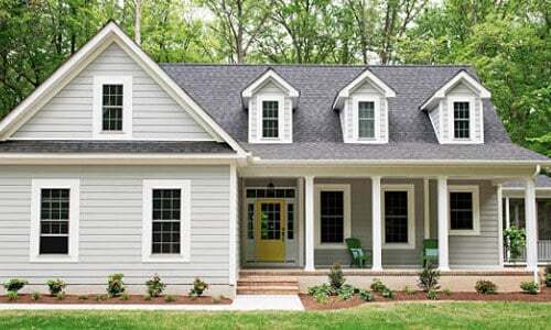 Example of a Cape Cod Style house. This house features hung windows with grids and a yellow front door with sidelites and a transom.