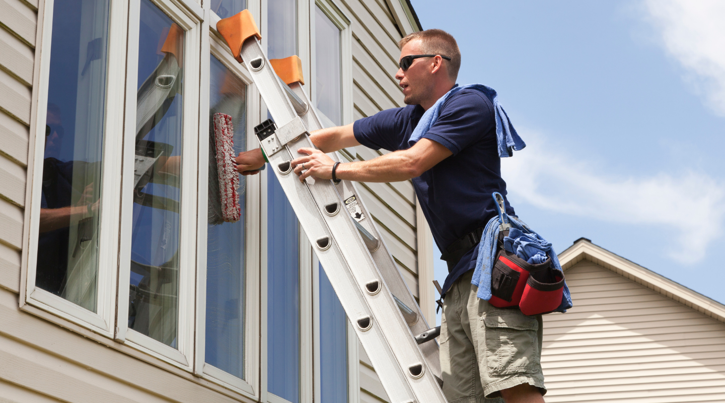 Photo of a man cleaning the window glass on a house. Photo from Shutterstock.