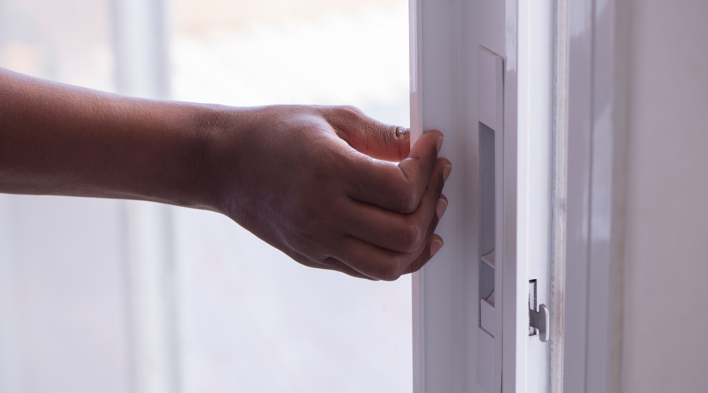 Person opening a sliding patio door. Image from Canva.