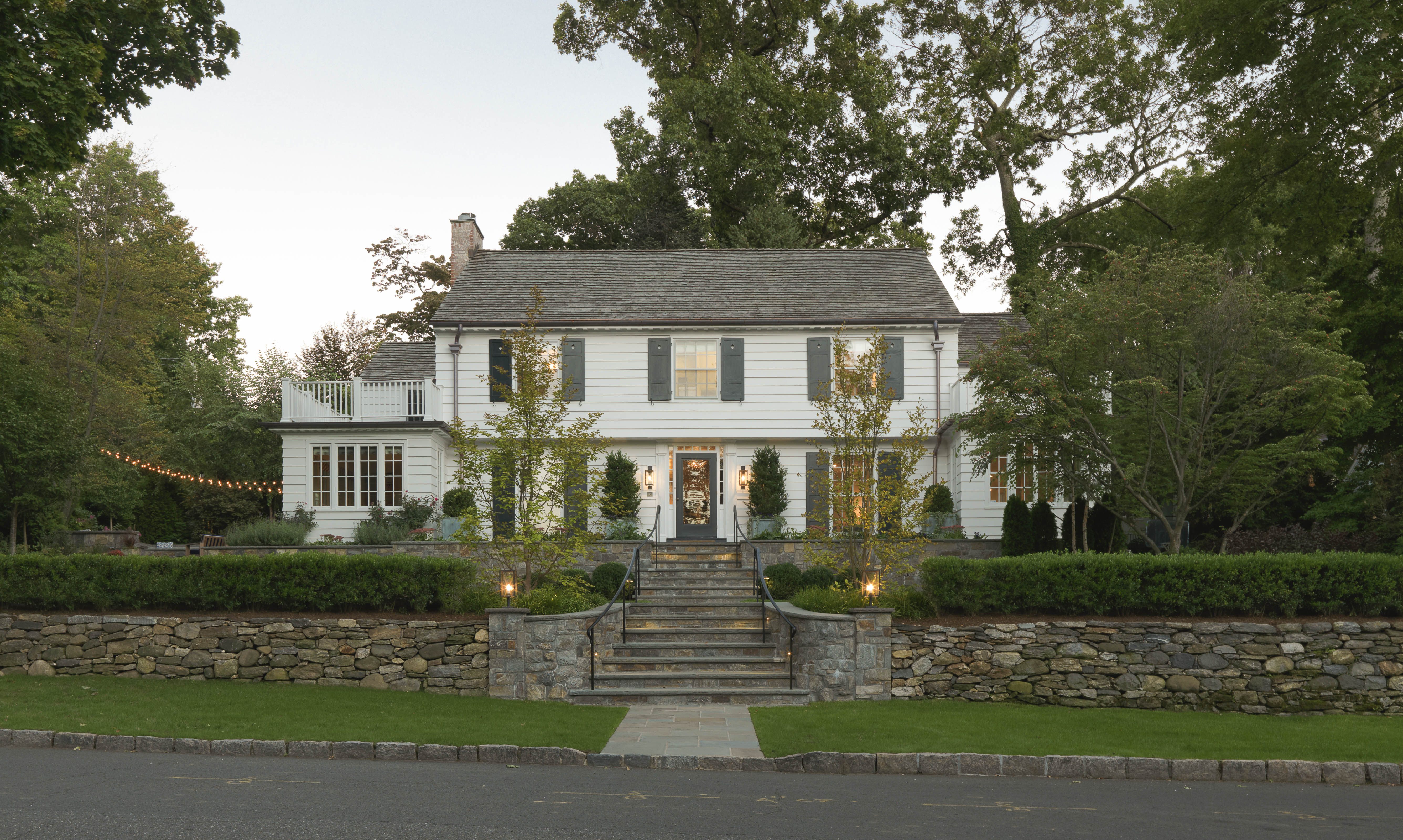 Two story suburban house with white siding and carefully manicured landscaping.