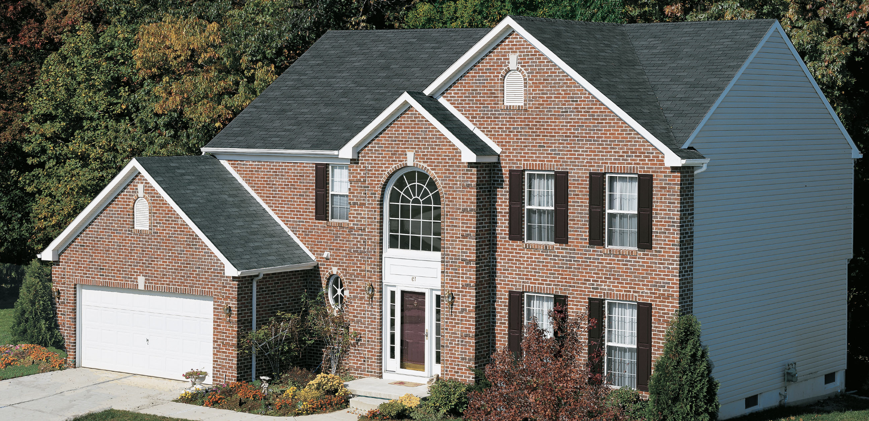 GAF asphalt shingles in charcoal atop a large brick home.