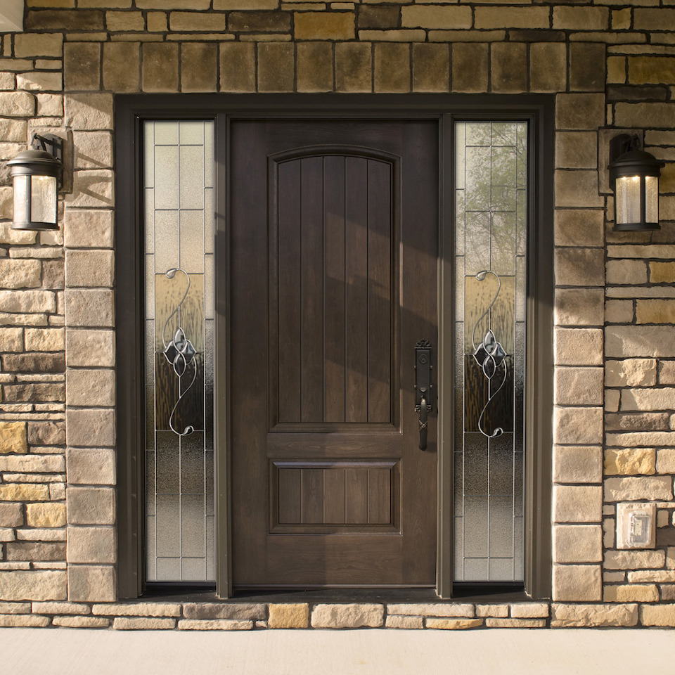 Dark stained front entry door with dark bronze hardware and sidelites with decorative glass on each side of the door.