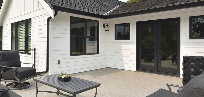 Black Milgard Ultra fiberglass hinged patio doors on house with white siding.