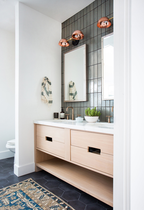 copper bathroom sconces with gold faucets black floor tile and wood vanity