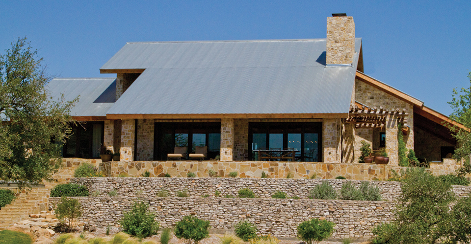 A corrugated metal roof on a stone facade home.