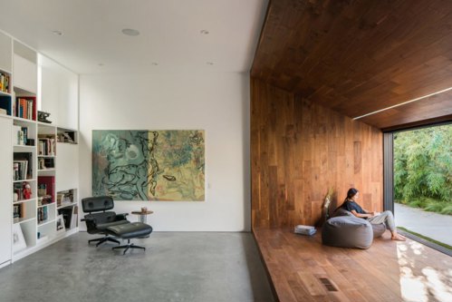 A reading nook surrounded by walnut walls facing sliding glass wall.