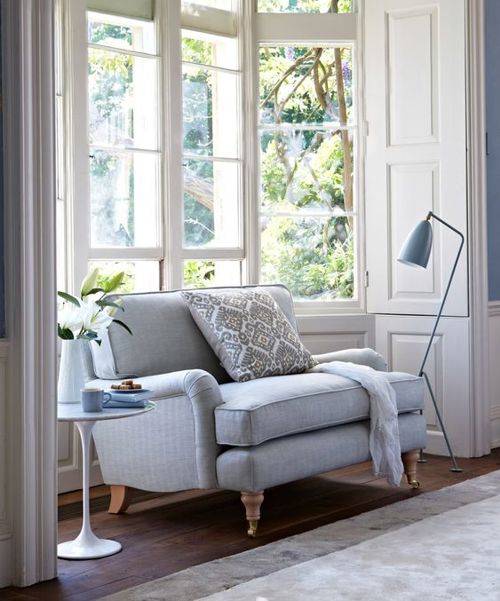 The classic reading nook with a loveseat, lamp, and side table in front of a bay window.