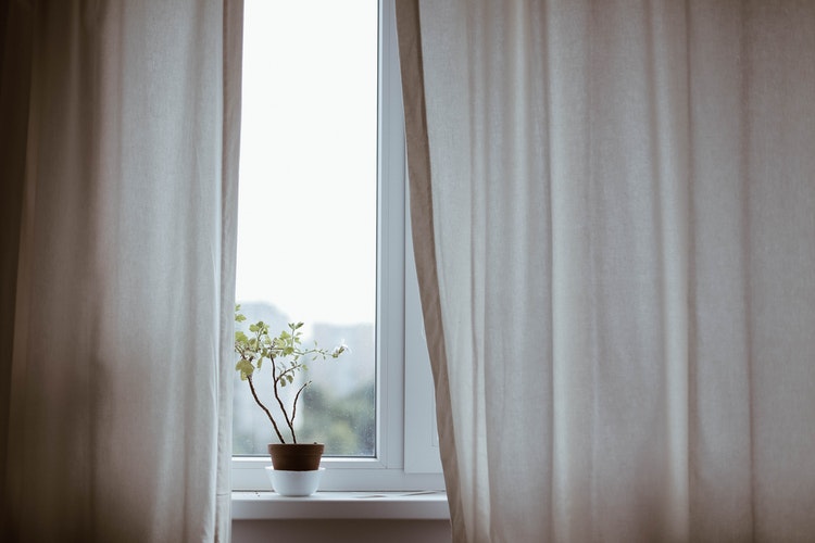 A well-dressed window is a good tool for additional protection from sun and wind. This photo has light fabric curtains as window coverings.
