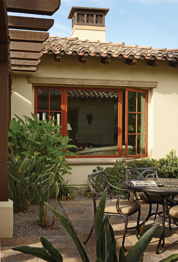 Photo of an exterior view of an Andersen E-Series window with a red finish. This shade of red is called Clay Canyon. The color of the window stands out brightly but nicely complements the reds in the tile roof and the light color of the stucco walls.