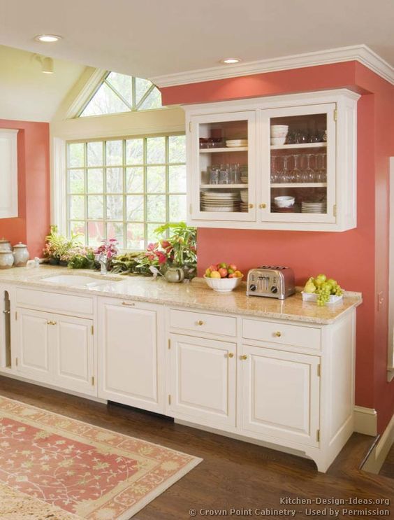 Kitchen featuring white cabinets, stone counters, coral walls, and walnut stained wood floors.