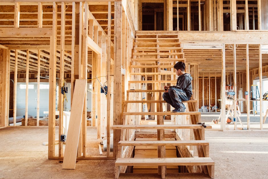 Boy sitting on wooden staircase in construction of timber home.