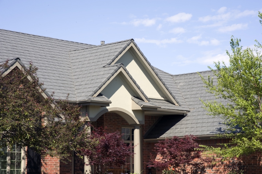 A grey DaVinci Roofscapes composite slate roof on a residential building with a red brick facade.