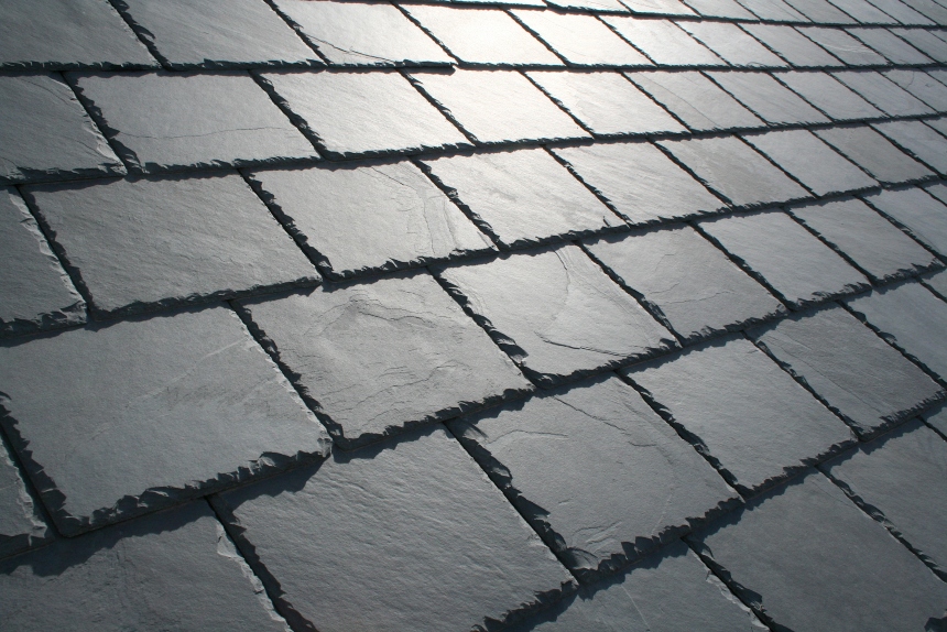 A close up of natural slate tiles on a roof reflecting a beam of sunlight.