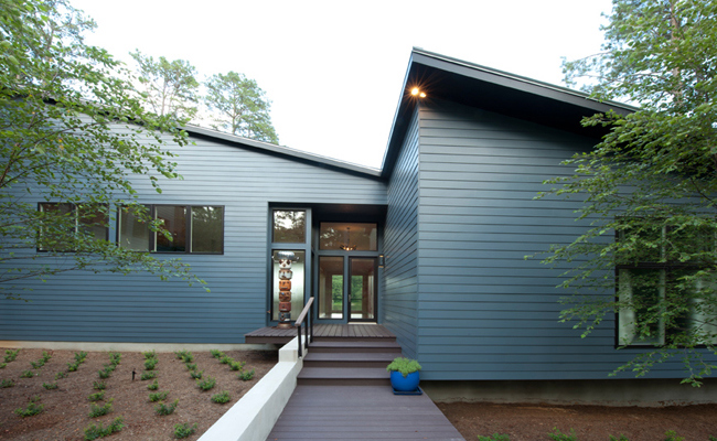 Modern house with sharp lines, navy blue horizontal siding and dark wood walkway
